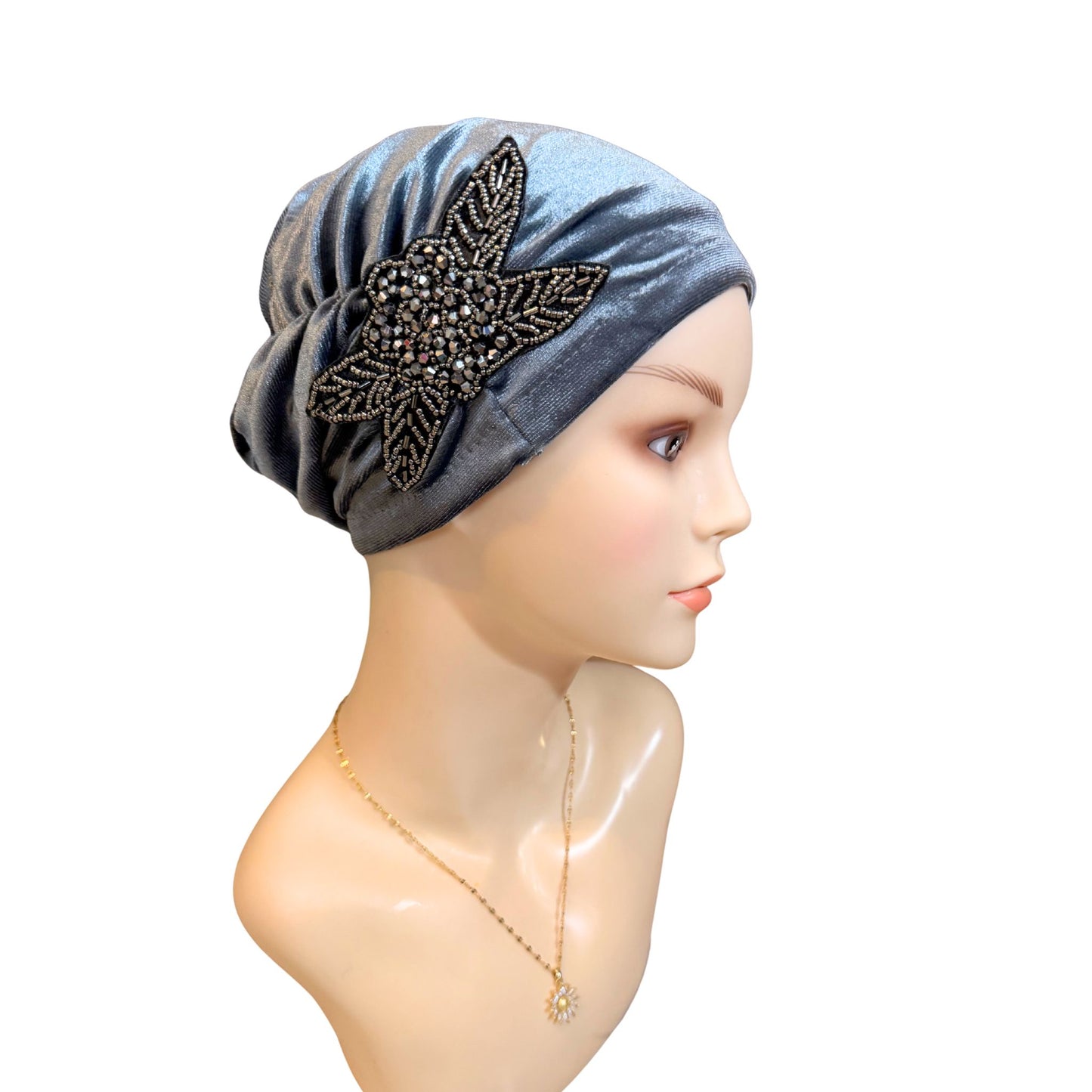 Gray headscarf with decorative leaf on a mannequin head against a white background