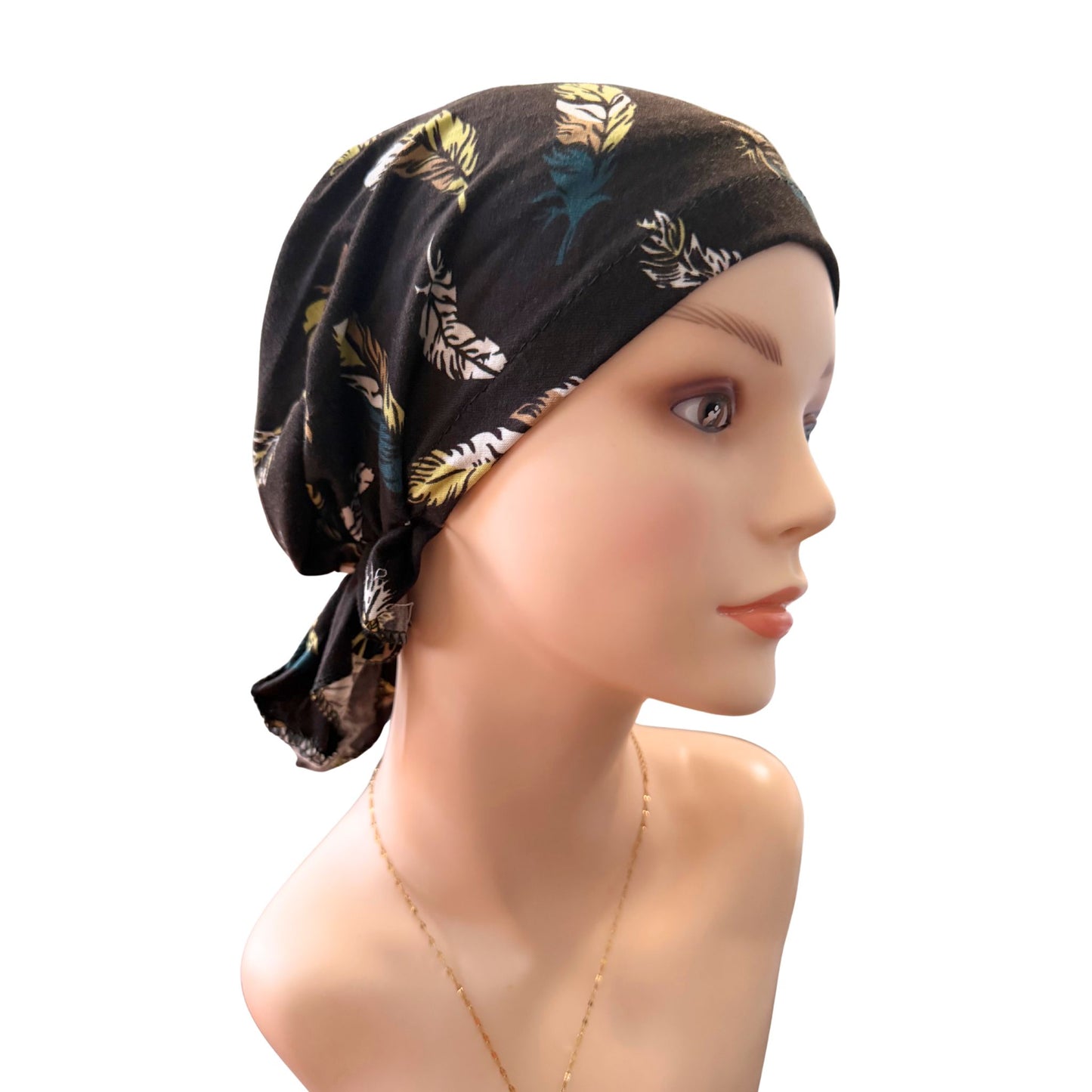Mannequin head wearing a black headscarf with feather pattern on a white background