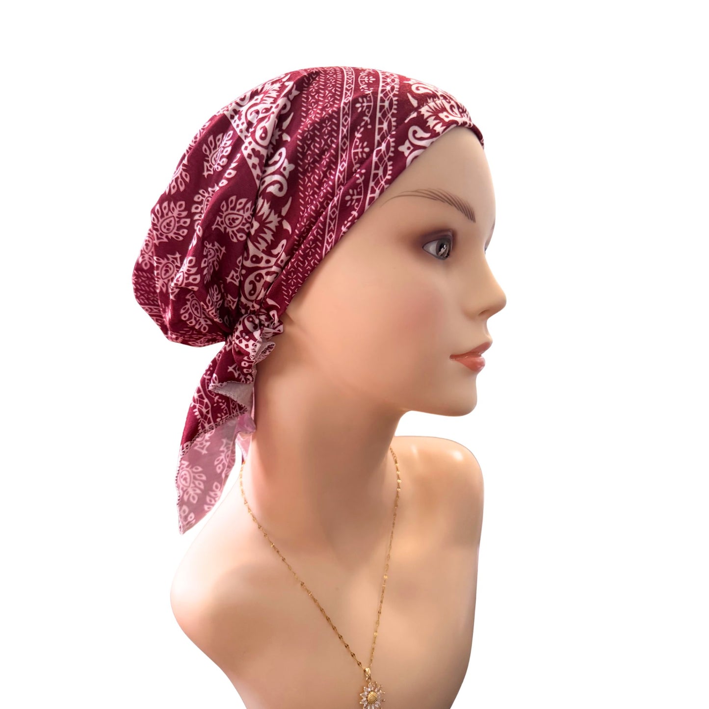 Mannequin head wearing a red patterned headscarf on a white background