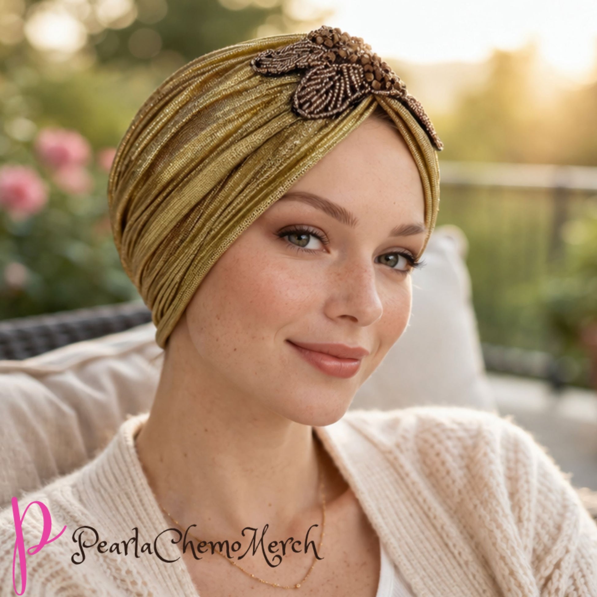 Woman wearing a gold alopecia turban with decorative elements, sitting outdoors.