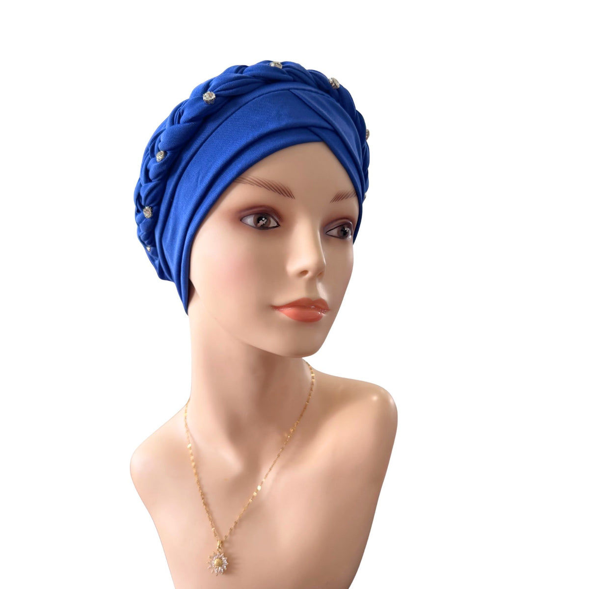 A royal blue knotted headwrap or turban-style headscarf displayed on a mannequin bust, with small decorative bead accents and a gold necklace against a plain white background.