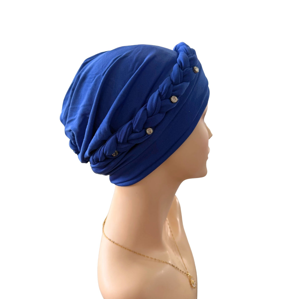 A royal blue fabric skullcap turban with a braided side detail and small decorative rhinestone accents, displayed on a mannequin head against a plain white background.