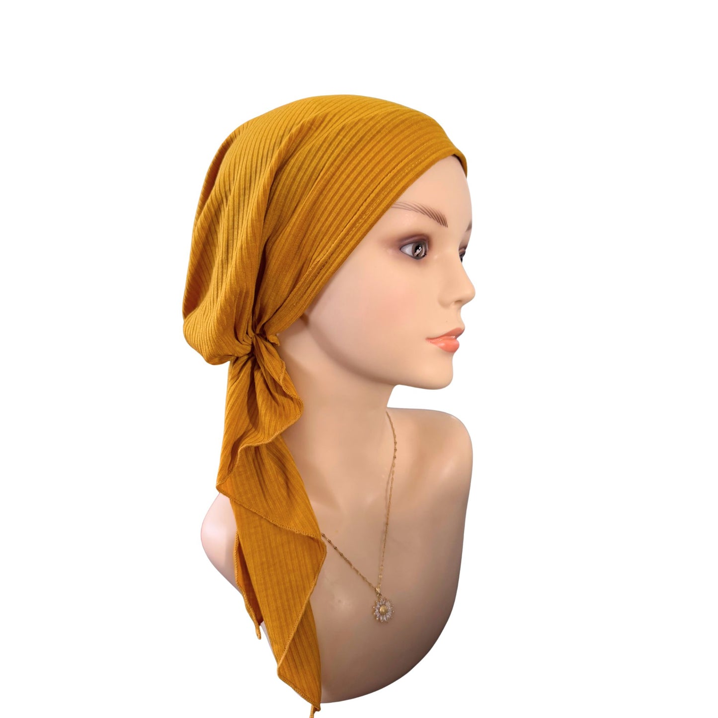 Mannequin head wearing a mustard yellow headscarf on a white background