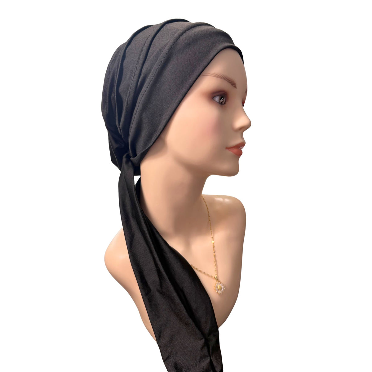 A black fabric headscarf or hijab wrapped around a mannequin head and neck, shown in side profile against a plain white background.