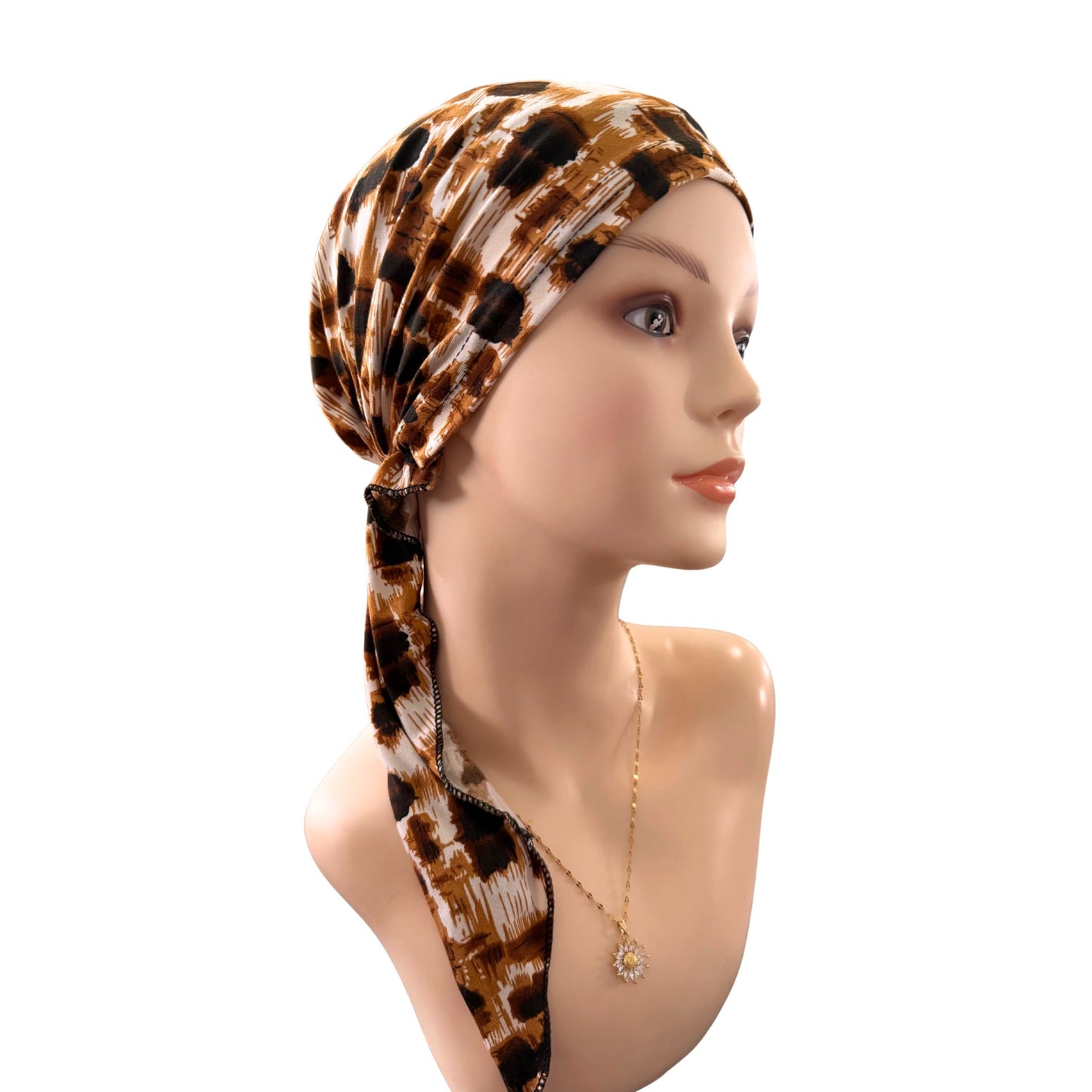 Mannequin head wearing a brown print headscarf on a white background