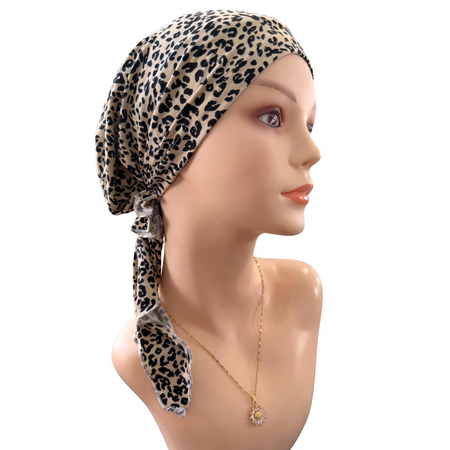 Mannequin head wearing a leopard print headscarf on a white background