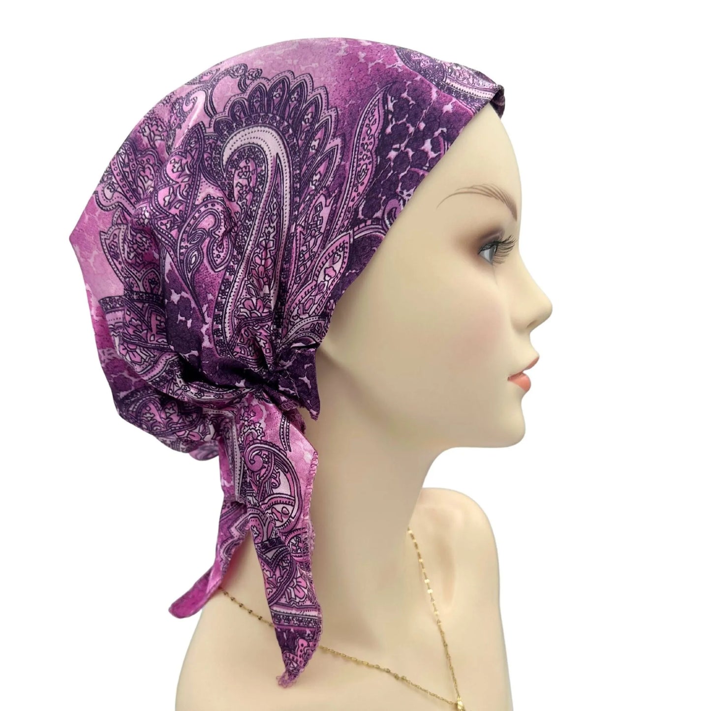 Mannequin head wearing a purple paisley patterned headscarf on a white background