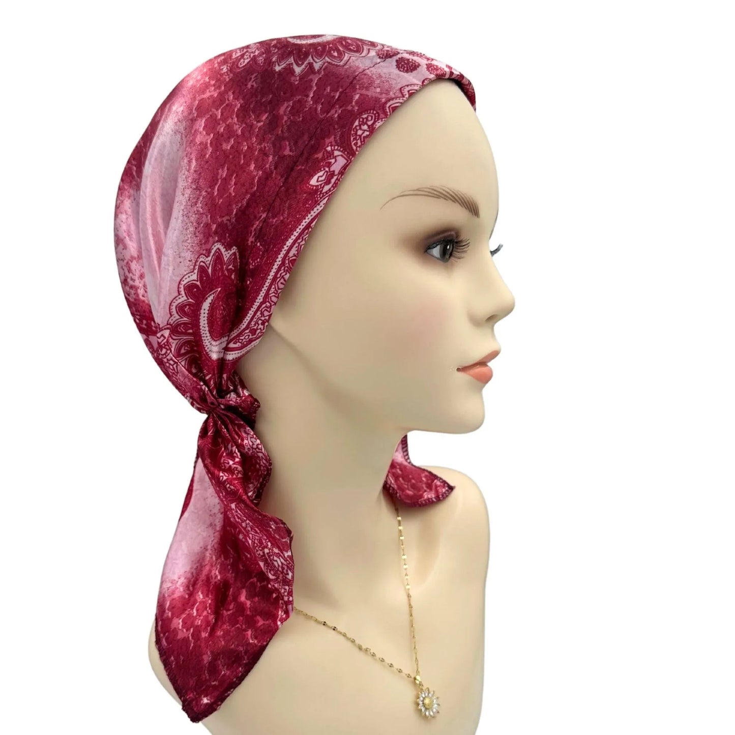 Mannequin head wearing a red patterned headscarf on a white background