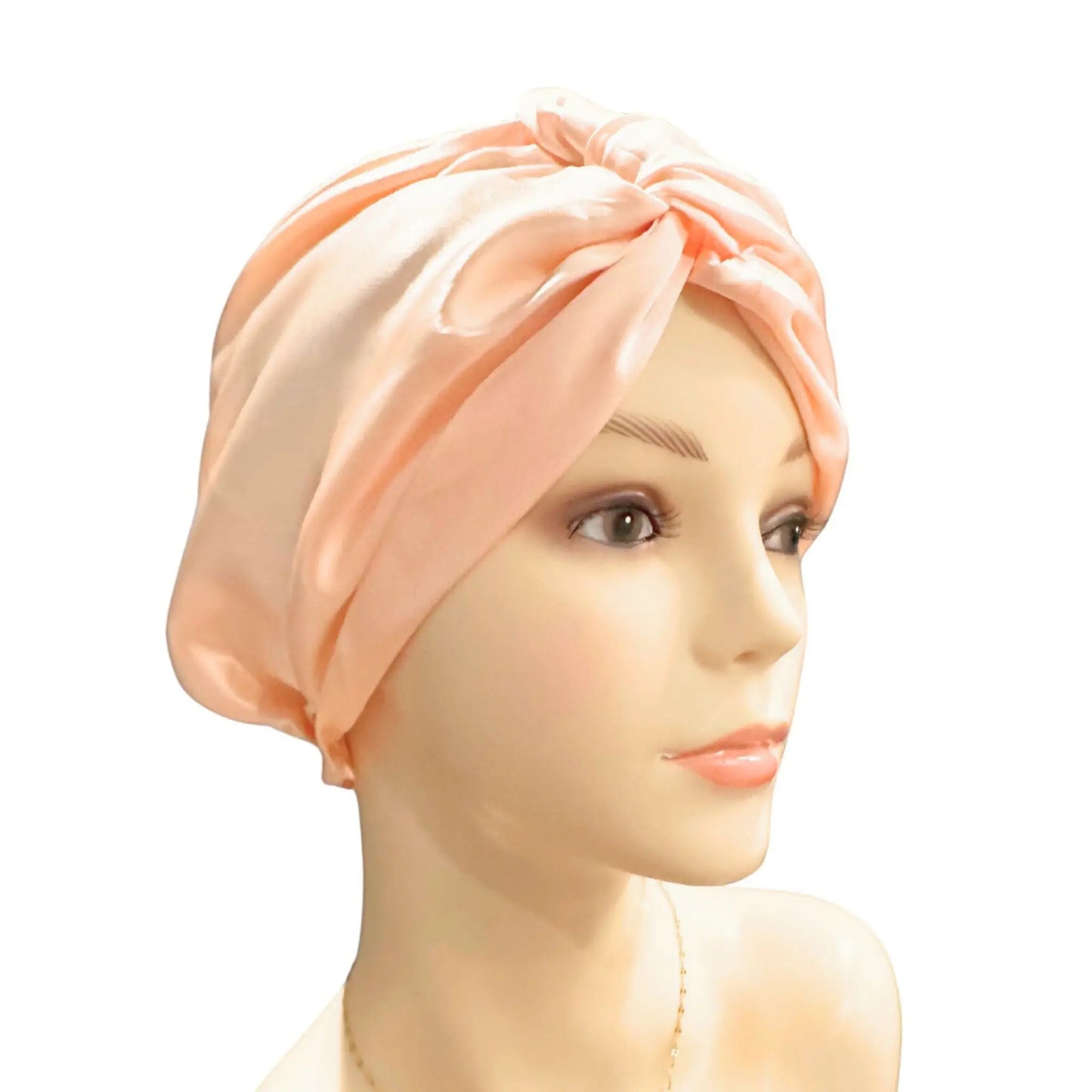 Mannequin head wearing a peach-colored silk turban on a white background