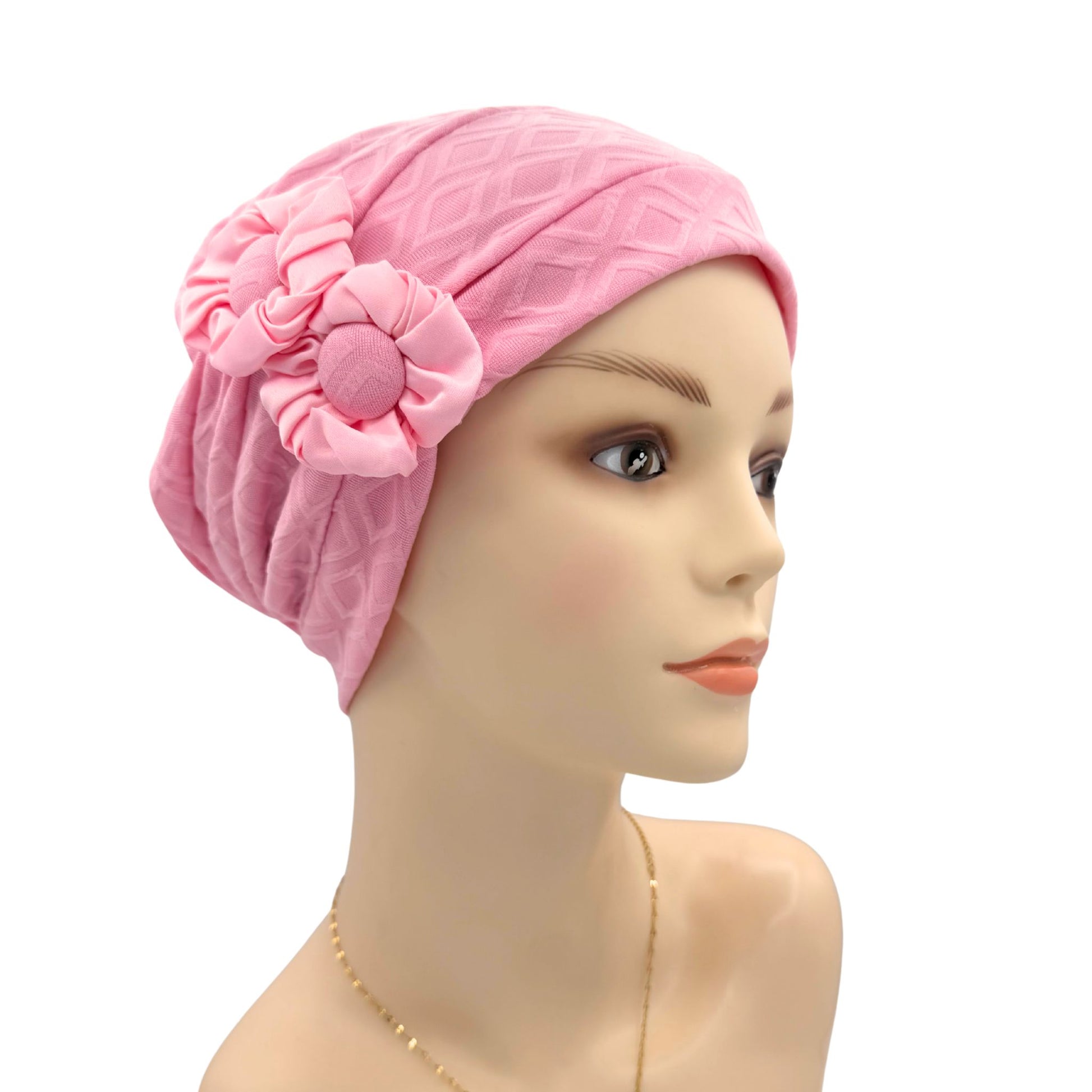 Pink headscarf with a flower on a mannequin head against a white background