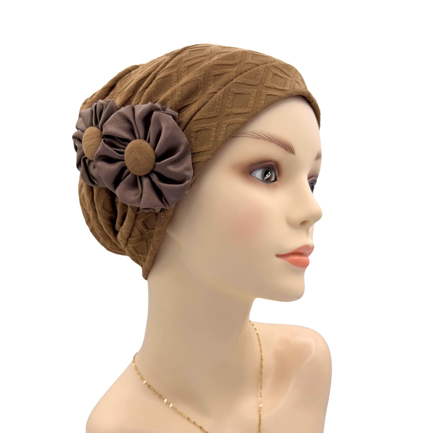 Brown headscarf with a flower accessory on a mannequin head against a white background